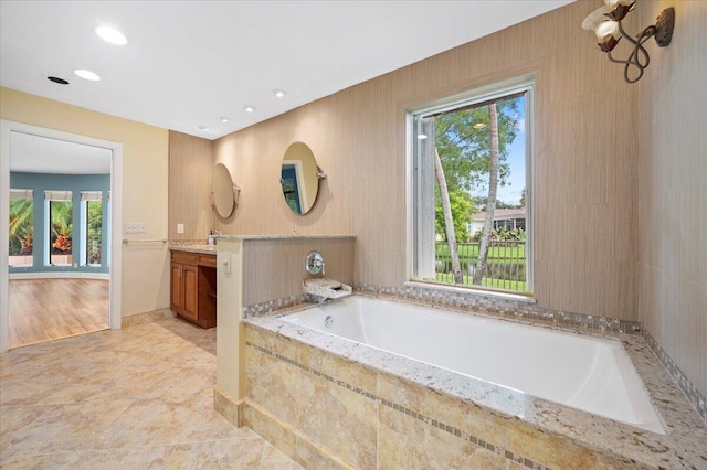 bathroom with vanity and tiled tub