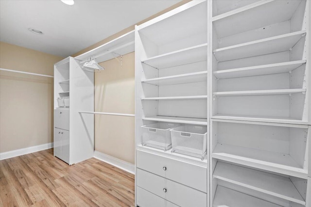 walk in closet with light hardwood / wood-style flooring