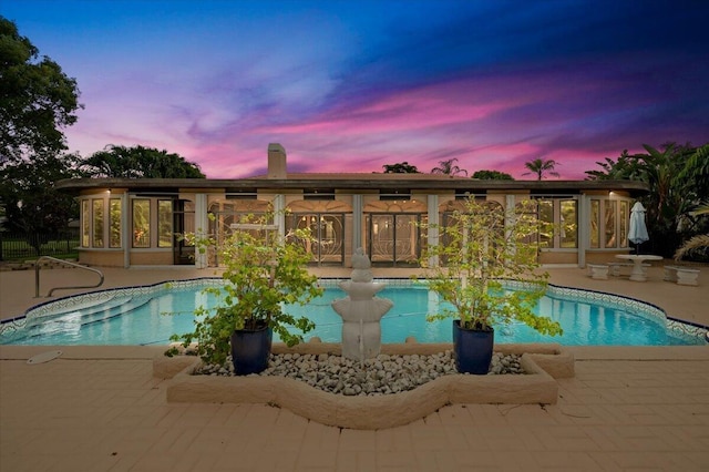 pool at dusk featuring a patio