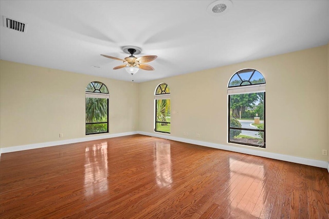 spare room featuring ceiling fan, a healthy amount of sunlight, and wood-type flooring