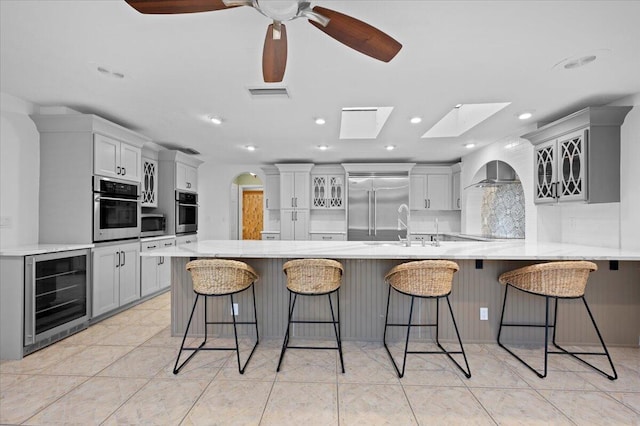 kitchen featuring a breakfast bar, a skylight, wine cooler, and stainless steel appliances