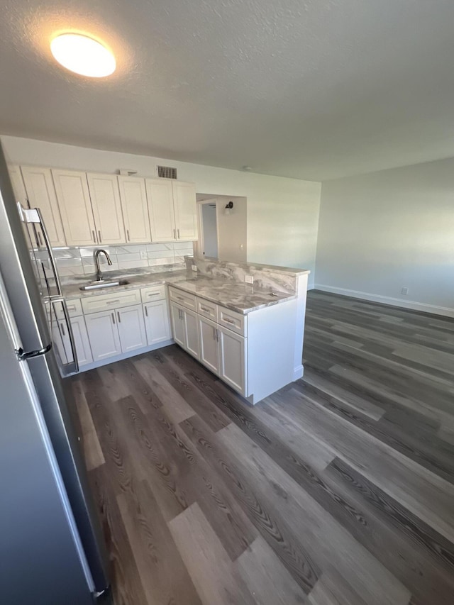 1010 Adams St, West Palm Beach, FL 33407 - kitchen with a sink, freestanding refrigerator, dark wood-style floors, a peninsula, and white cabinetry