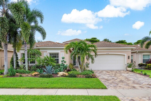 mediterranean / spanish home with a garage and a front lawn