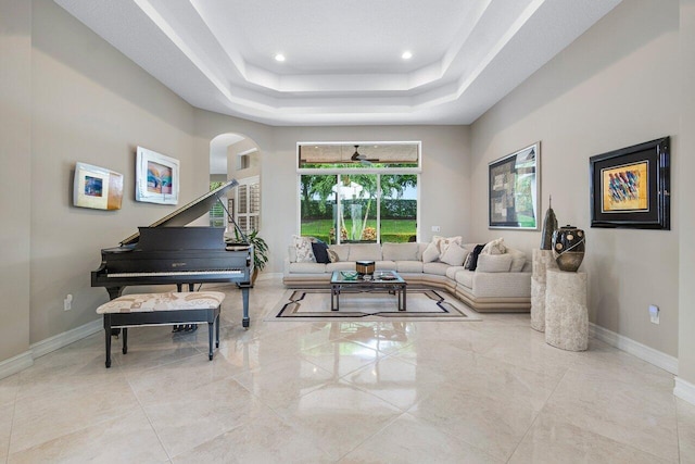 living room featuring a raised ceiling and a healthy amount of sunlight