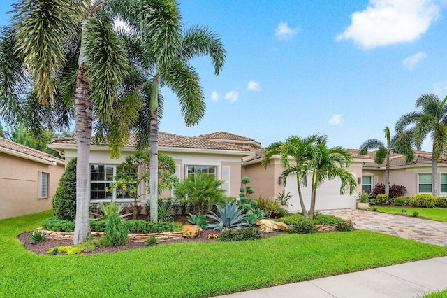 mediterranean / spanish house with a garage and a front lawn