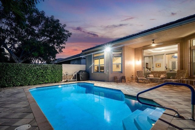 pool at dusk with a patio area and outdoor lounge area