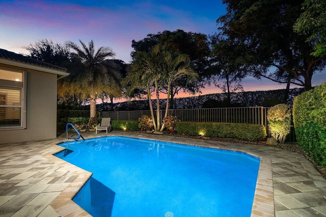 pool at dusk featuring a patio