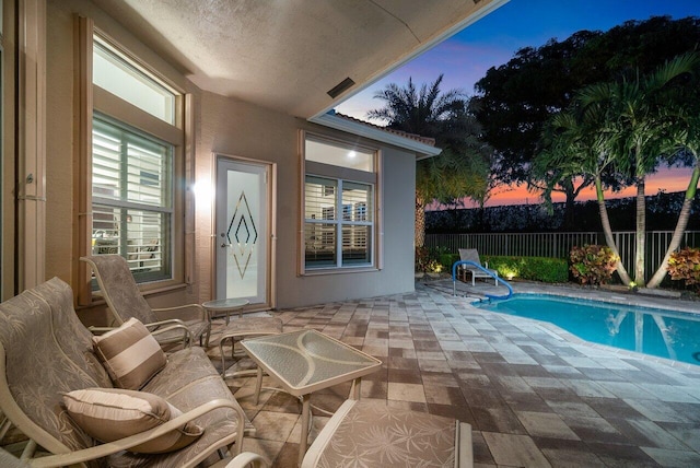 pool at dusk featuring a patio