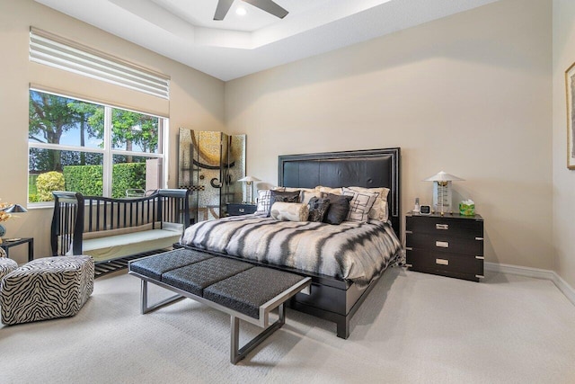 carpeted bedroom with a tray ceiling and ceiling fan