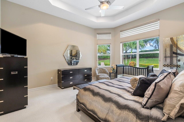 bedroom with carpet flooring, multiple windows, ceiling fan, and a tray ceiling