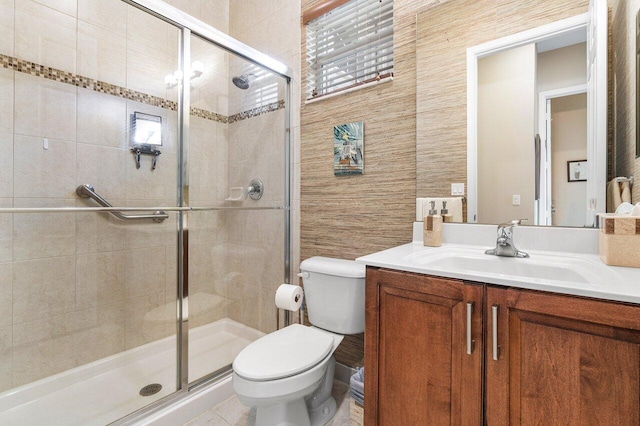 bathroom featuring a shower with door, tile patterned floors, toilet, tile walls, and vanity