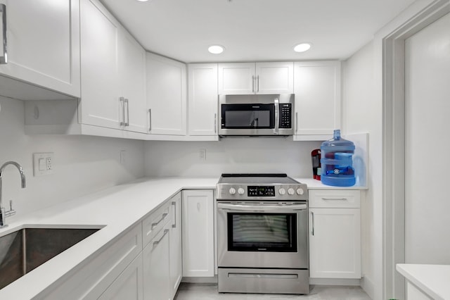 kitchen with appliances with stainless steel finishes, white cabinetry, and sink