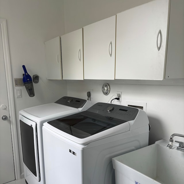 washroom featuring sink, independent washer and dryer, and cabinets