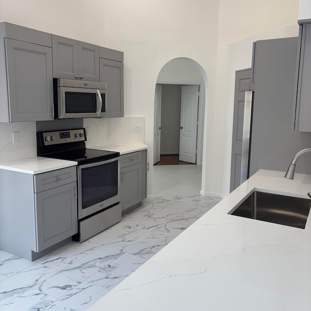 kitchen featuring stainless steel appliances, sink, and gray cabinetry