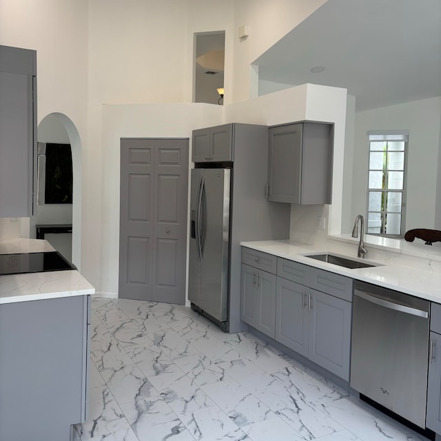 kitchen featuring gray cabinets, sink, appliances with stainless steel finishes, and vaulted ceiling