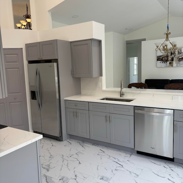 kitchen featuring gray cabinetry, appliances with stainless steel finishes, sink, hanging light fixtures, and lofted ceiling