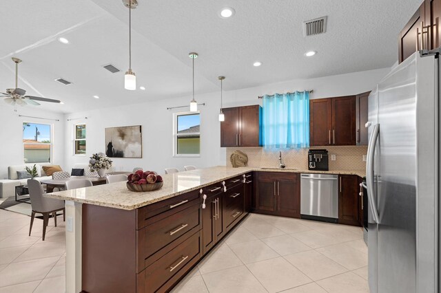 kitchen featuring sink, kitchen peninsula, pendant lighting, decorative backsplash, and appliances with stainless steel finishes