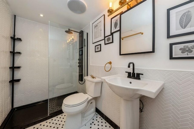 bathroom with tile walls, toilet, tile patterned floors, and a tile shower