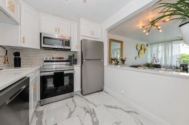 kitchen featuring backsplash, stainless steel appliances, sink, a chandelier, and white cabinets