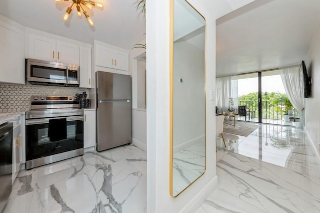 kitchen featuring appliances with stainless steel finishes, tasteful backsplash, an inviting chandelier, and white cabinets