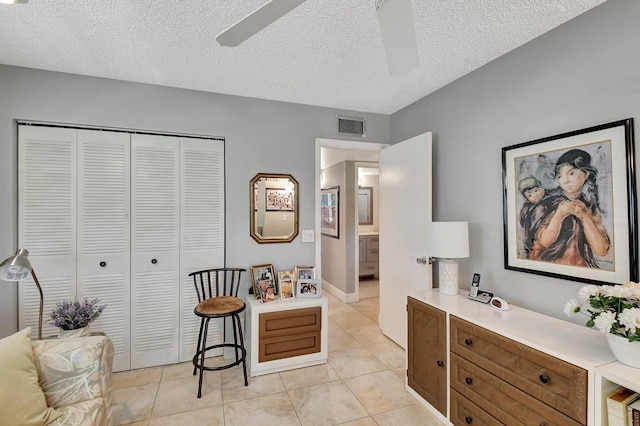 interior space featuring a textured ceiling, ceiling fan, and light tile patterned floors