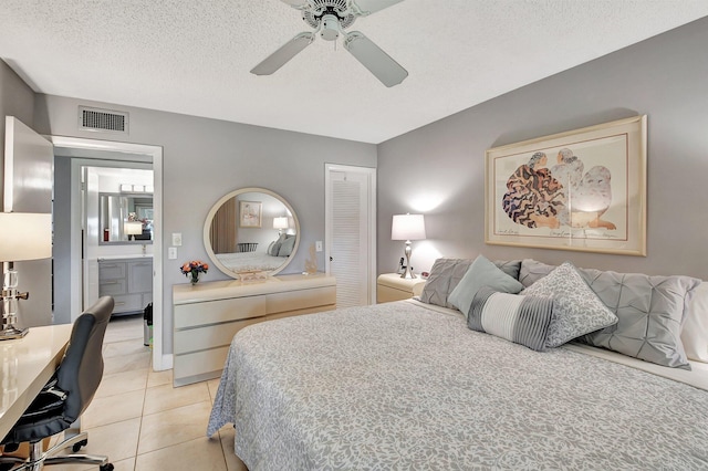 bedroom with ceiling fan, light tile patterned floors, ensuite bathroom, and a textured ceiling