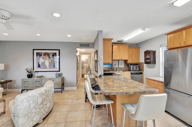 kitchen with a kitchen island, sink, ceiling fan, appliances with stainless steel finishes, and a breakfast bar area