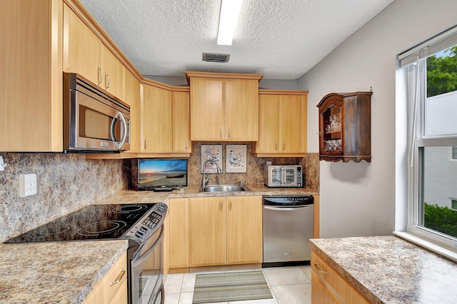 kitchen with light tile patterned floors, light brown cabinetry, and stainless steel appliances