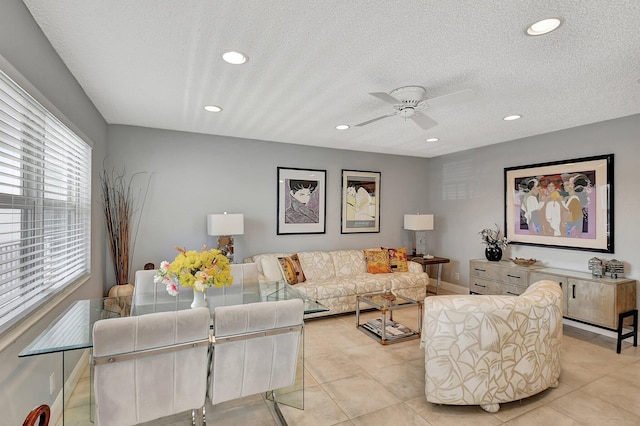 living room with a textured ceiling, light tile patterned floors, and ceiling fan