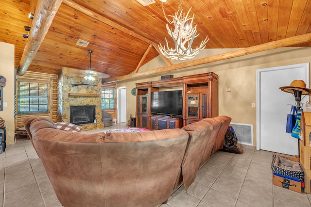 tiled living room featuring lofted ceiling with beams, a healthy amount of sunlight, an inviting chandelier, and a stone fireplace