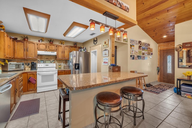 kitchen featuring light tile patterned floors, light stone counters, stainless steel appliances, a kitchen breakfast bar, and pendant lighting