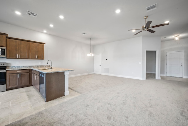 kitchen with kitchen peninsula, appliances with stainless steel finishes, light colored carpet, sink, and hanging light fixtures