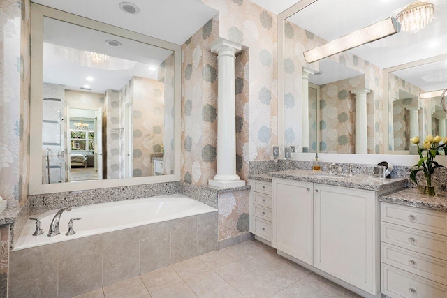 bathroom featuring tiled tub, vanity, ornate columns, and tile patterned floors