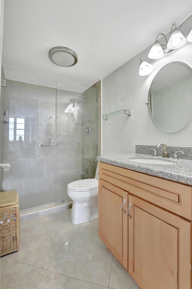 bathroom featuring tile patterned flooring, vanity, toilet, and a shower with shower door