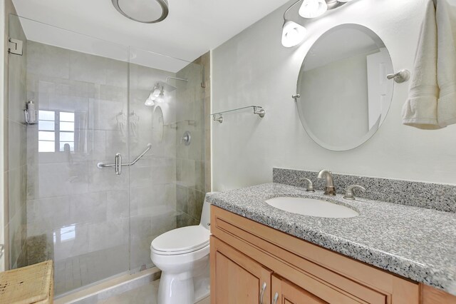 bathroom featuring an enclosed shower, toilet, and vanity