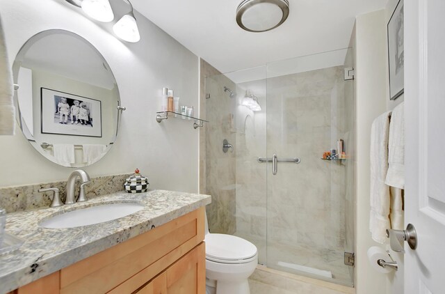 bathroom featuring tile patterned floors, vanity, toilet, and a shower with shower door