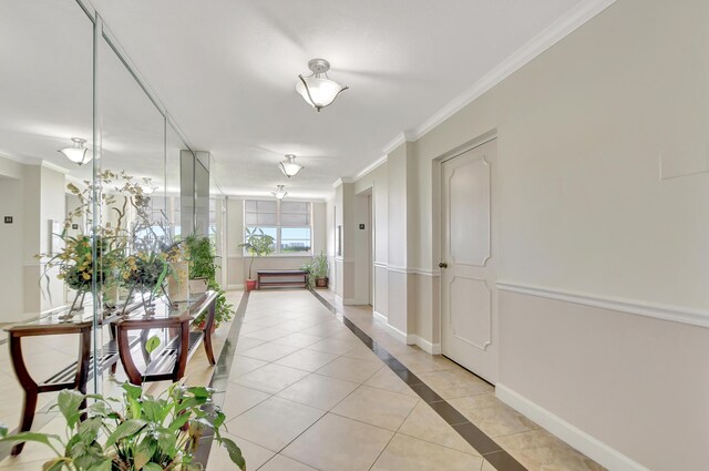 hall with ornamental molding and light tile patterned floors