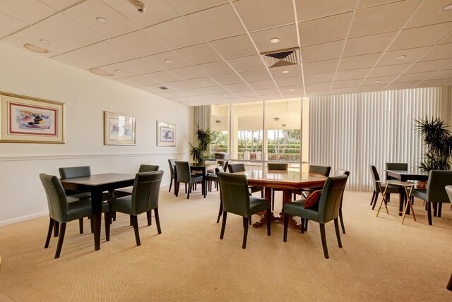 dining area featuring light colored carpet and a drop ceiling