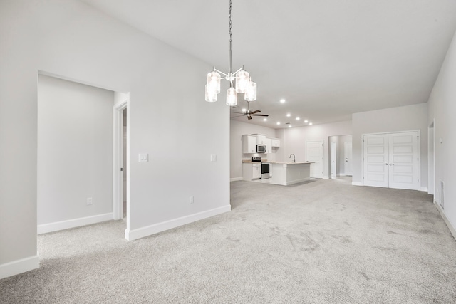 unfurnished living room with light carpet, ceiling fan with notable chandelier, and sink