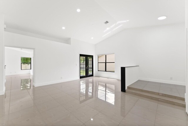 empty room featuring french doors, vaulted ceiling, and plenty of natural light