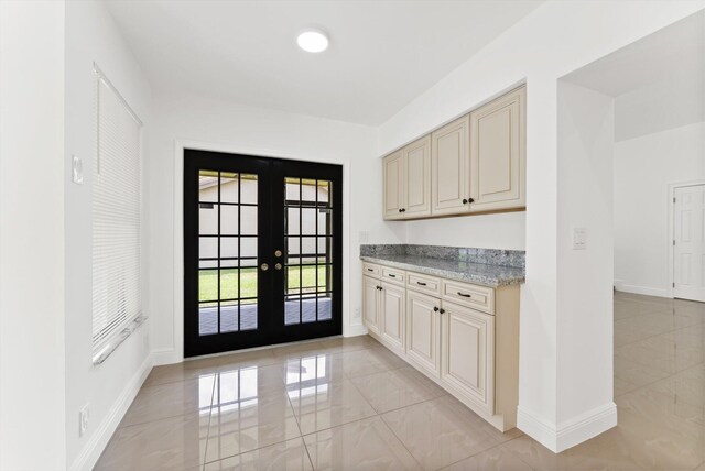 interior space with light stone counters, cream cabinetry, and french doors