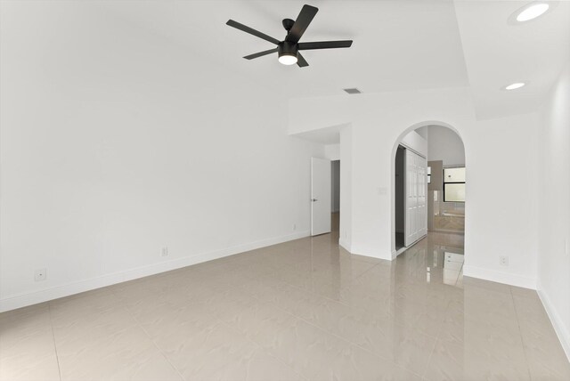 tiled empty room featuring lofted ceiling and ceiling fan