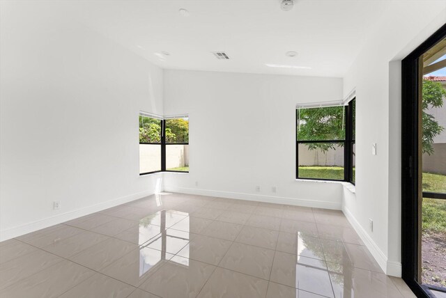 unfurnished room with light tile patterned flooring and vaulted ceiling