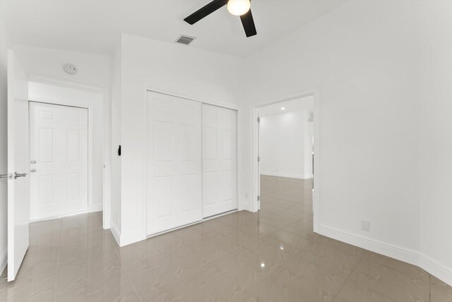 unfurnished bedroom with ceiling fan and a closet