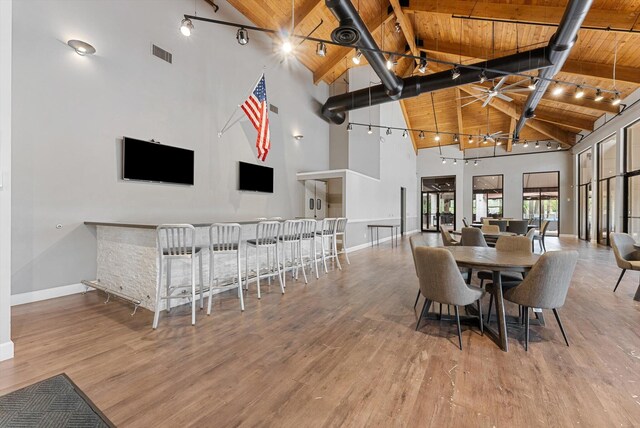 dining room with light hardwood / wood-style flooring, high vaulted ceiling, beamed ceiling, and wooden ceiling