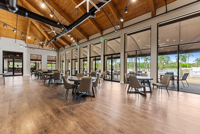 dining area featuring hardwood / wood-style floors, high vaulted ceiling, and beamed ceiling