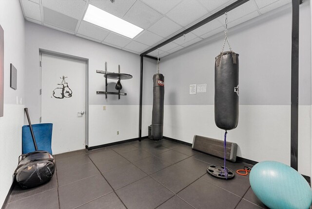 workout area with dark tile patterned flooring and a drop ceiling