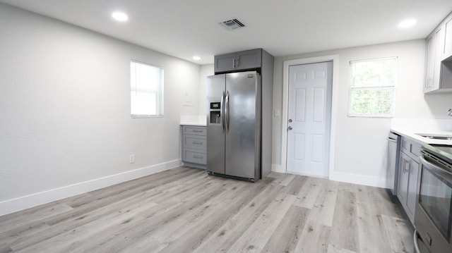 kitchen with sink, gray cabinets, stainless steel appliances, light hardwood / wood-style floors, and decorative backsplash