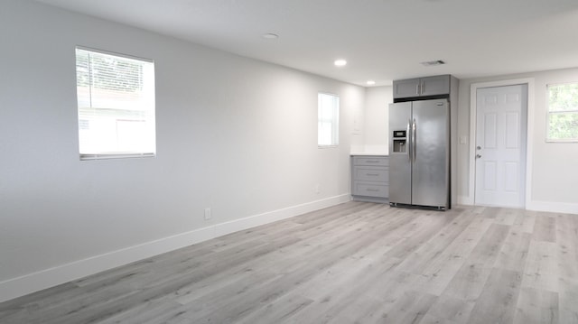 kitchen with appliances with stainless steel finishes, a wealth of natural light, gray cabinetry, and light hardwood / wood-style floors