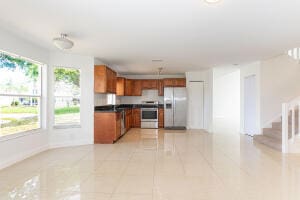 kitchen featuring stainless steel range oven, white refrigerator with ice dispenser, and light tile patterned flooring